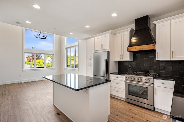 kitchen with light wood-type flooring, backsplash, premium range hood, a kitchen island, and high quality appliances