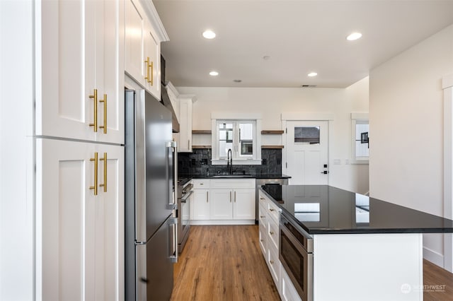 kitchen with white cabinets, sink, a kitchen island, light hardwood / wood-style floors, and appliances with stainless steel finishes