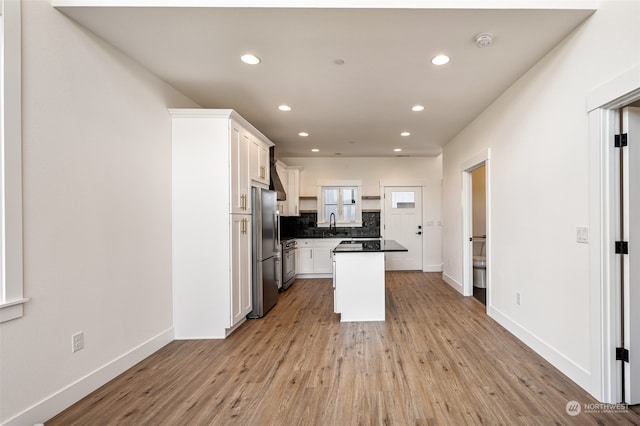 kitchen featuring decorative backsplash, light wood-type flooring, white cabinets, and stainless steel fridge