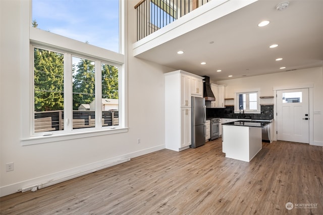 kitchen featuring white cabinets, custom exhaust hood, appliances with stainless steel finishes, and a wealth of natural light