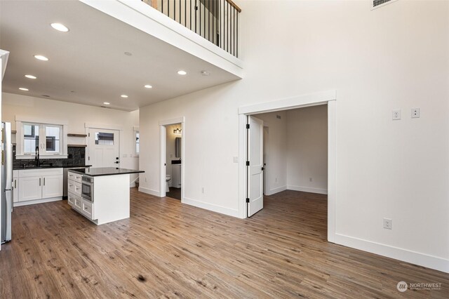 kitchen with white cabinets, stainless steel oven, light hardwood / wood-style flooring, and decorative backsplash