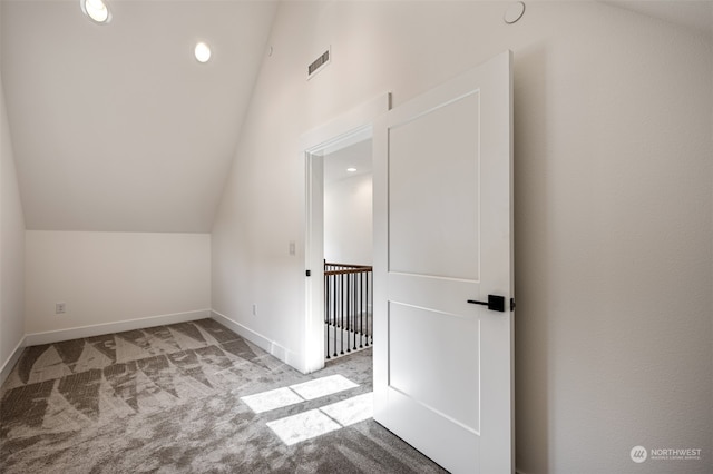 additional living space featuring light carpet and vaulted ceiling