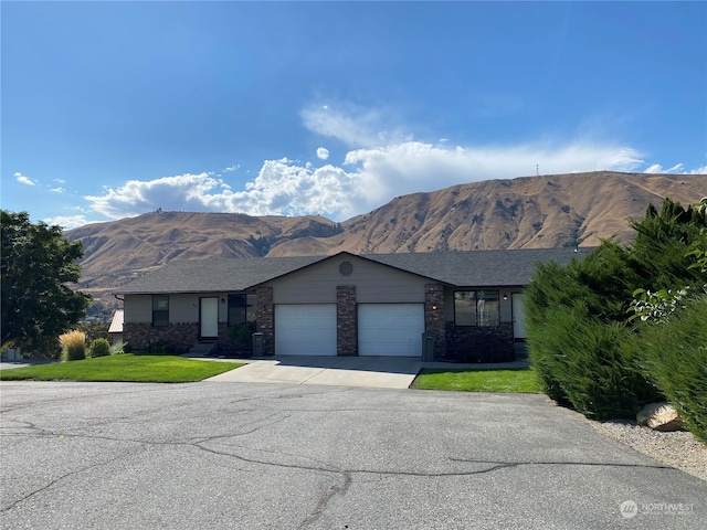 ranch-style home with a garage, a mountain view, and a front yard