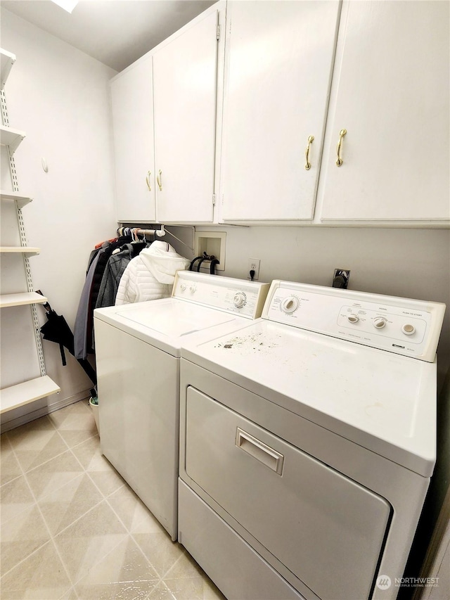 laundry area featuring washer and dryer, light tile patterned floors, and cabinets