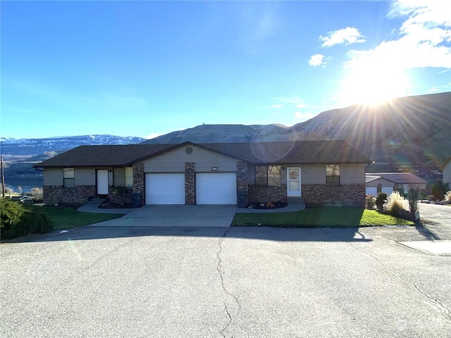 single story home with a garage, driveway, a mountain view, and a front lawn