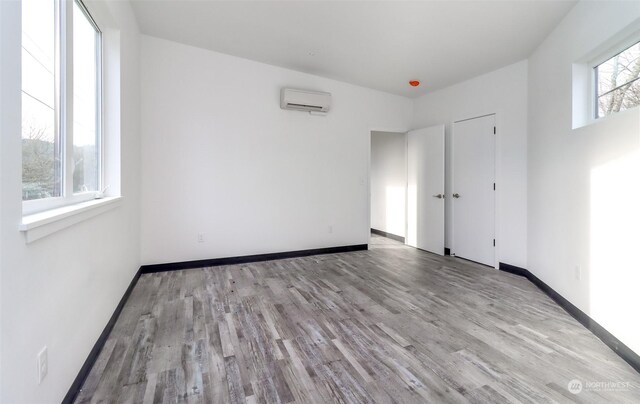 empty room with a wall mounted air conditioner and wood-type flooring