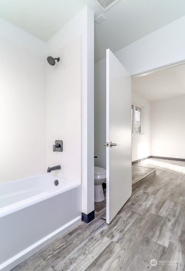 bathroom featuring shower / washtub combination, wood-type flooring, and toilet