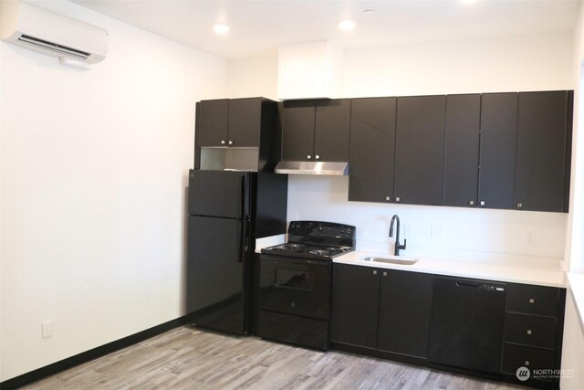 kitchen with a wall mounted AC, black appliances, light hardwood / wood-style flooring, and sink