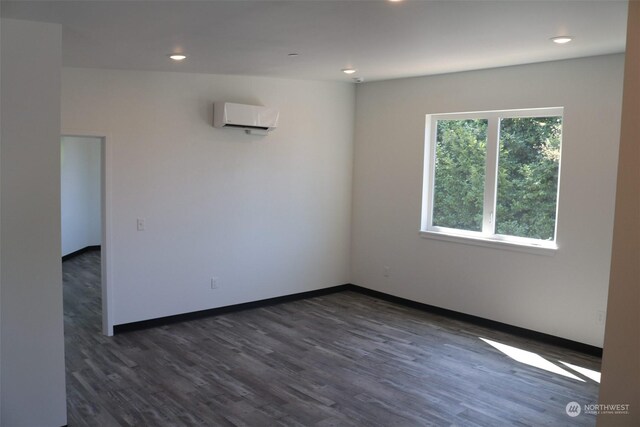 unfurnished room with an AC wall unit and dark wood-type flooring