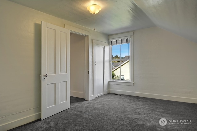 additional living space featuring dark colored carpet and vaulted ceiling