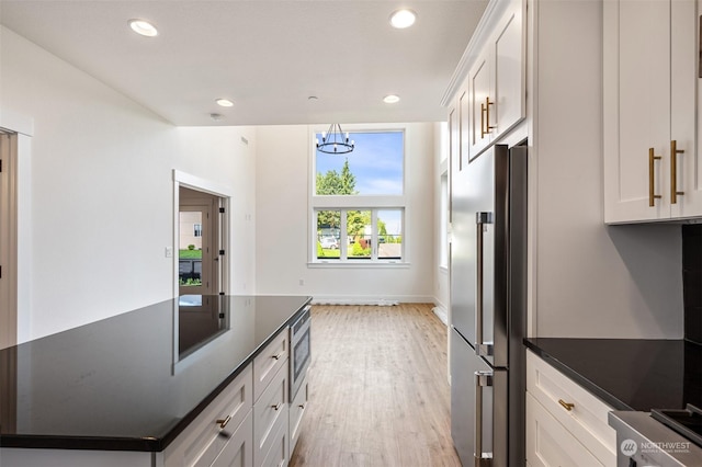 kitchen featuring light hardwood / wood-style floors, stainless steel refrigerator, and white cabinets