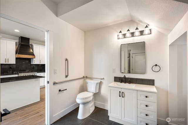 bathroom with lofted ceiling, tasteful backsplash, vanity, tile patterned floors, and toilet