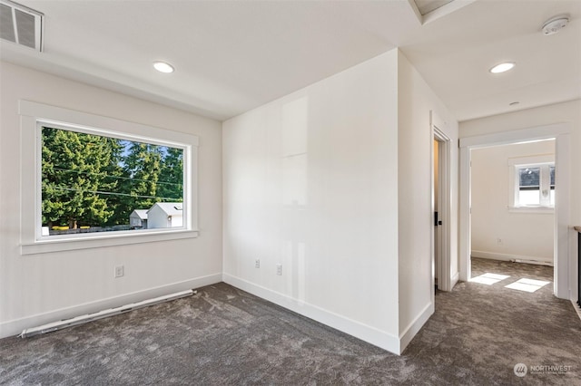 empty room featuring plenty of natural light and dark carpet