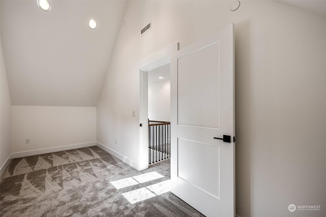 additional living space featuring light colored carpet and vaulted ceiling