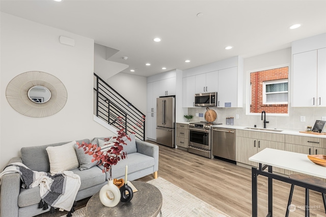 kitchen with white cabinetry, sink, stainless steel appliances, light hardwood / wood-style floors, and decorative backsplash