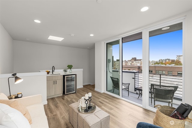 living room featuring indoor wet bar, light wood-type flooring, and beverage cooler