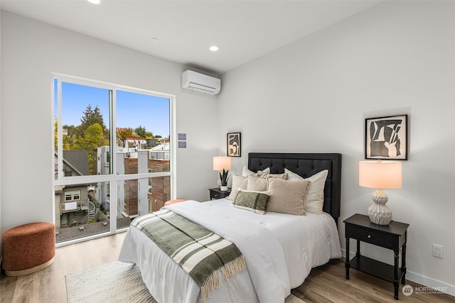 bedroom featuring a wall unit AC, hardwood / wood-style floors, and access to outside