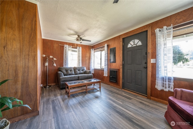 living room with dark hardwood / wood-style floors, a textured ceiling, wooden walls, and ceiling fan