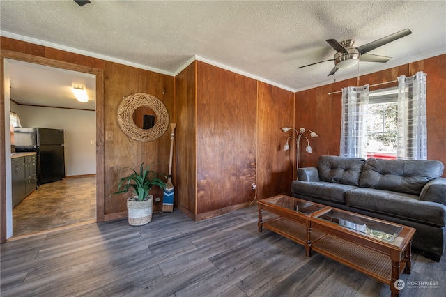 living room with wood walls, a textured ceiling, ceiling fan, and dark hardwood / wood-style flooring