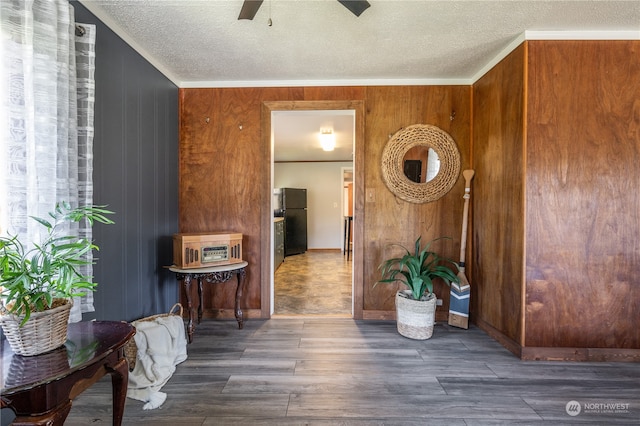 interior space with a textured ceiling, wooden walls, and dark hardwood / wood-style flooring