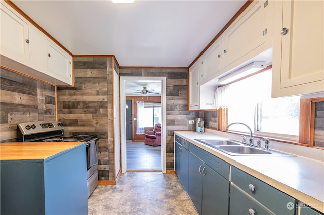 kitchen with ceiling fan, white cabinetry, wooden walls, and electric range