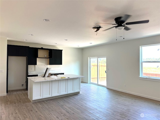 kitchen with light stone countertops, ceiling fan, plenty of natural light, and light hardwood / wood-style floors