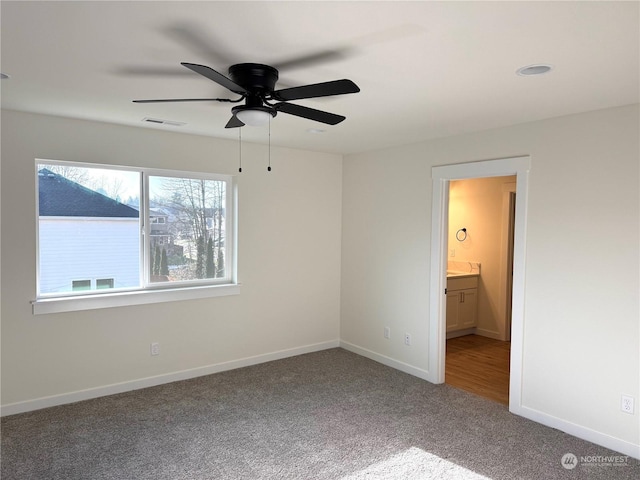 unfurnished bedroom with ceiling fan, carpet floors, and connected bathroom