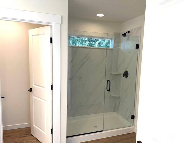 bathroom with hardwood / wood-style flooring and a shower with door