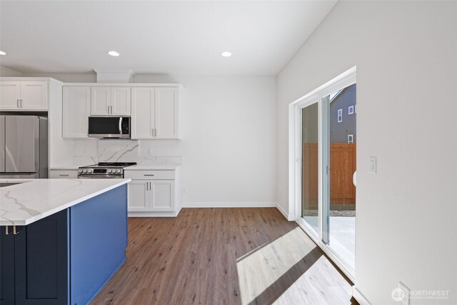 11114 NE 91st Ave, Vancouver, WA 98662 - kitchen featuring light stone countertops, appliances with stainless steel finishes, white cabinets, baseboards, and light wood-type flooring