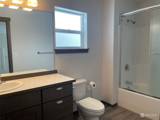 full bathroom featuring wood-type flooring, toilet, bath / shower combo with glass door, and vanity