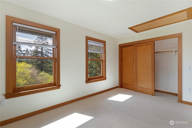 unfurnished bedroom featuring light colored carpet, a closet, and multiple windows