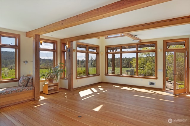 unfurnished sunroom featuring beamed ceiling and a wealth of natural light