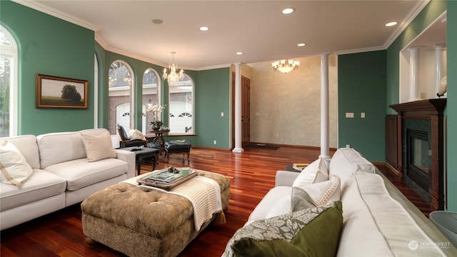 living room with crown molding, dark hardwood / wood-style floors, a notable chandelier, and ornate columns