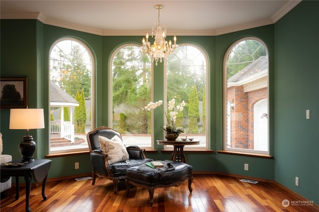 living area featuring crown molding, hardwood / wood-style floors, and a chandelier