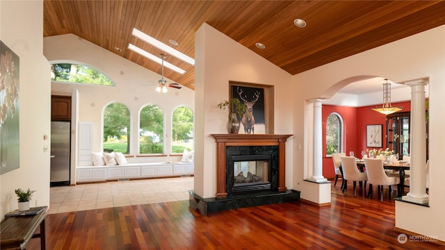 tiled living room featuring plenty of natural light, high vaulted ceiling, ceiling fan, a high end fireplace, and decorative columns