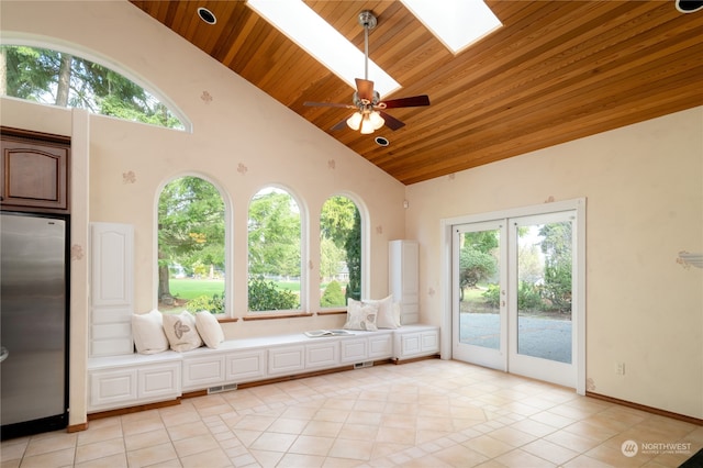 unfurnished sunroom featuring vaulted ceiling with skylight, ceiling fan, and wooden ceiling