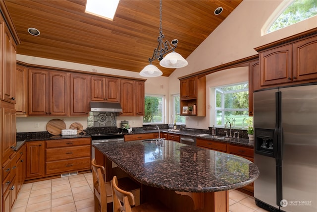 kitchen featuring light tile floors, decorative light fixtures, a kitchen island with sink, and appliances with stainless steel finishes