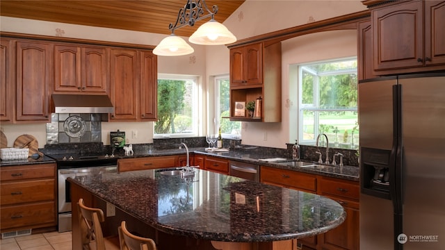 kitchen featuring hanging light fixtures, sink, an island with sink, light tile floors, and stainless steel appliances