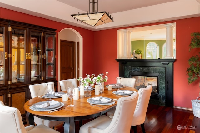 dining space with a premium fireplace, dark hardwood / wood-style floors, and decorative columns