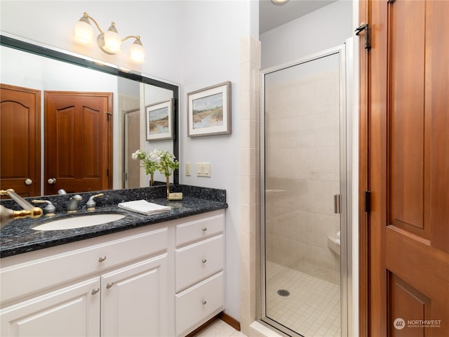 bathroom featuring a shower with shower door and vanity