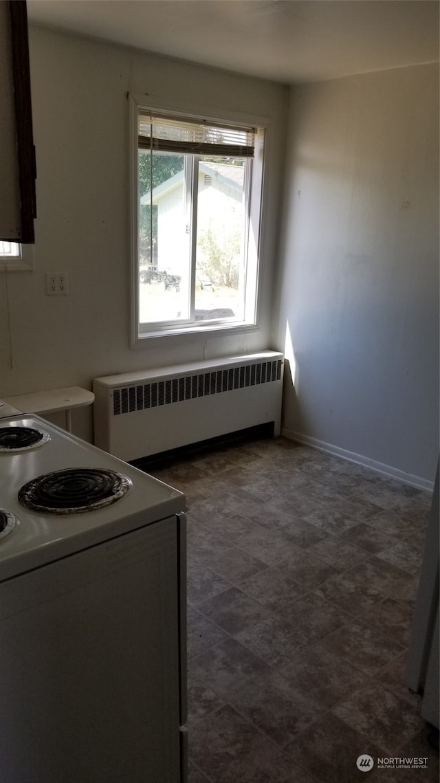 kitchen featuring dark tile flooring, radiator heating unit, and electric range