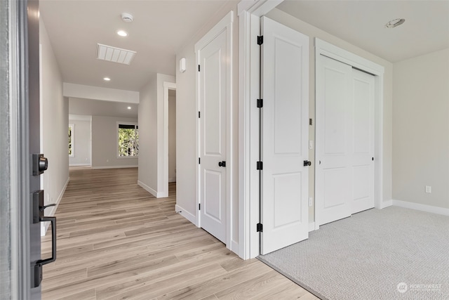 hall featuring light wood finished floors, recessed lighting, visible vents, and baseboards