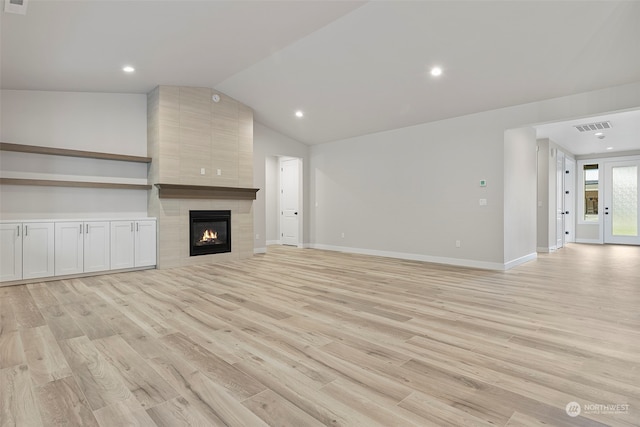 unfurnished living room featuring light wood-style floors, lofted ceiling, visible vents, and a fireplace