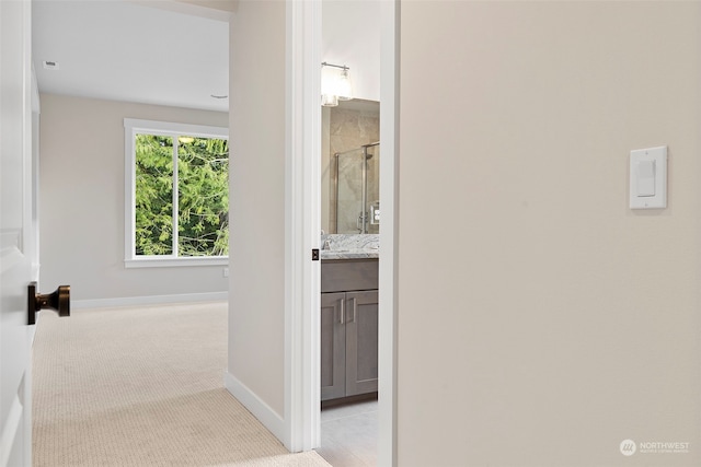 hallway with light colored carpet and baseboards