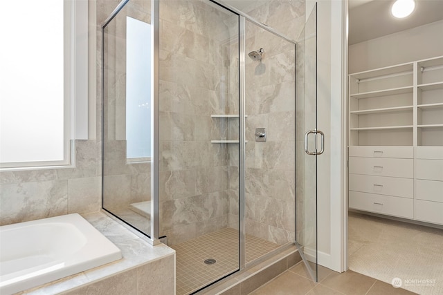 bathroom with a stall shower, a spacious closet, a bath, and tile patterned floors