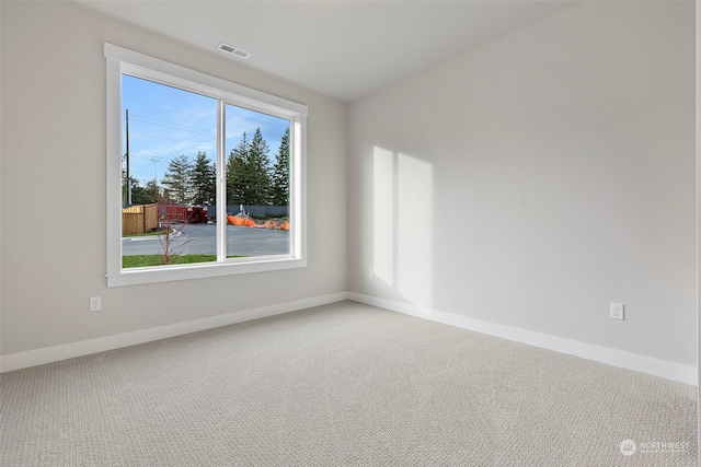 carpeted spare room with visible vents and baseboards