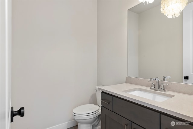 bathroom featuring toilet, baseboards, a chandelier, and vanity