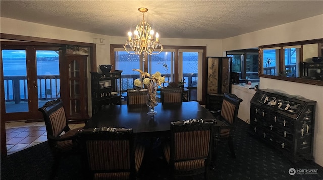 dining room with an inviting chandelier, dark tile flooring, and a textured ceiling