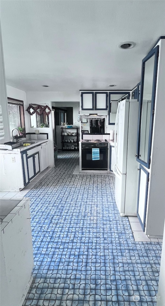 kitchen featuring white cabinets, stove, white fridge, and sink