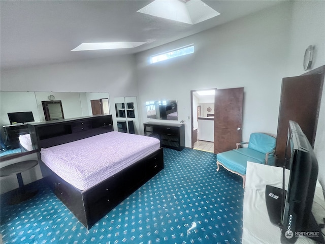 carpeted bedroom with a skylight, connected bathroom, and a high ceiling